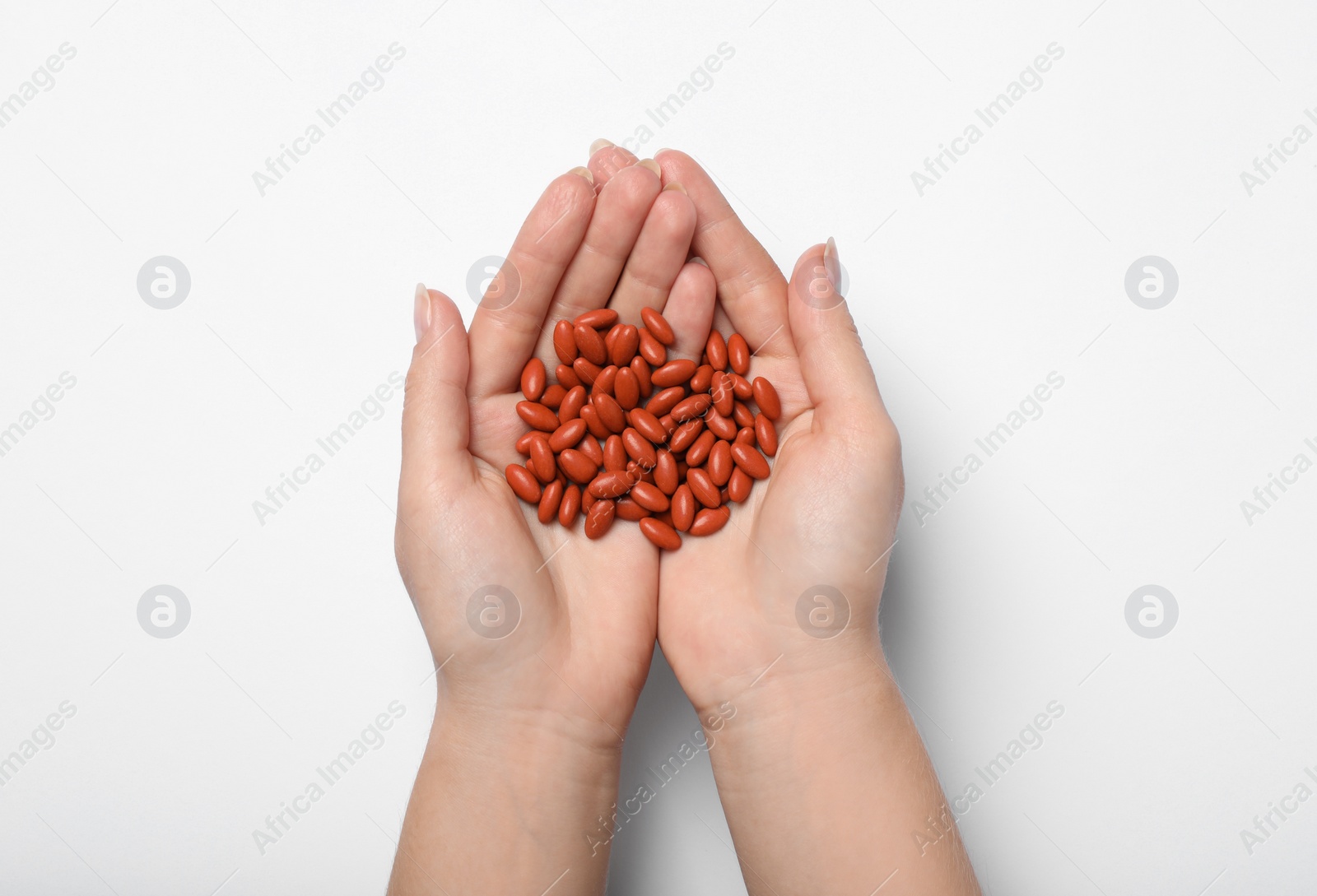 Photo of Woman holding pills on white background, top view. Anemia treatment