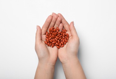 Photo of Woman holding pills on white background, top view. Anemia treatment