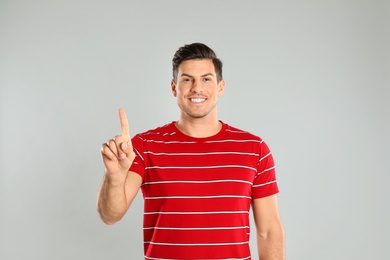 Photo of Man showing number one with his hand on grey background