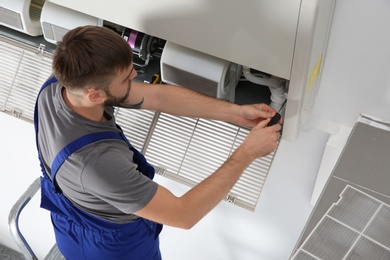 Photo of Young male technician repairing air conditioner indoors