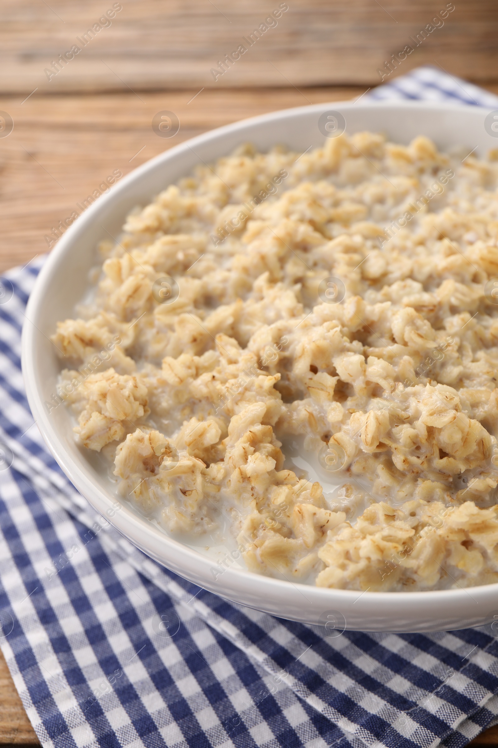 Photo of Tasty boiled oatmeal in bowl on table, closeup