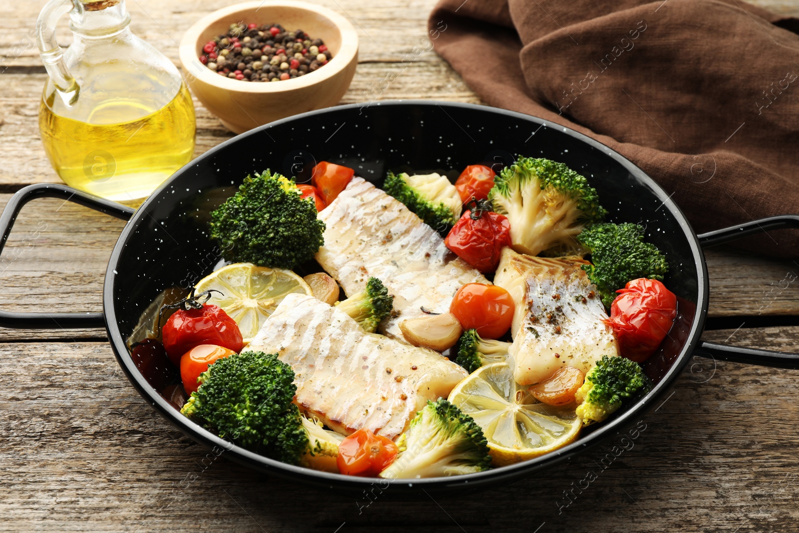 Photo of Tasty cod cooked with vegetables in frying pan on wooden table