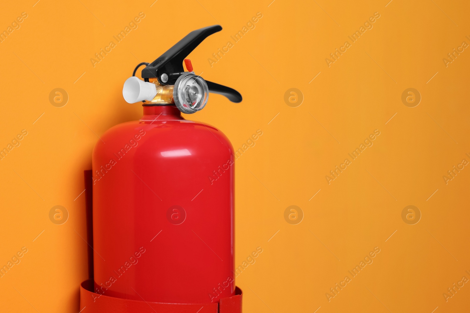 Photo of Red fire extinguisher on orange background. Space for text