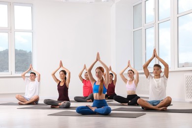 Photo of Group of people practicing yoga on mats indoors, space for text