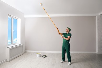 Photo of Man painting ceiling with roller in room