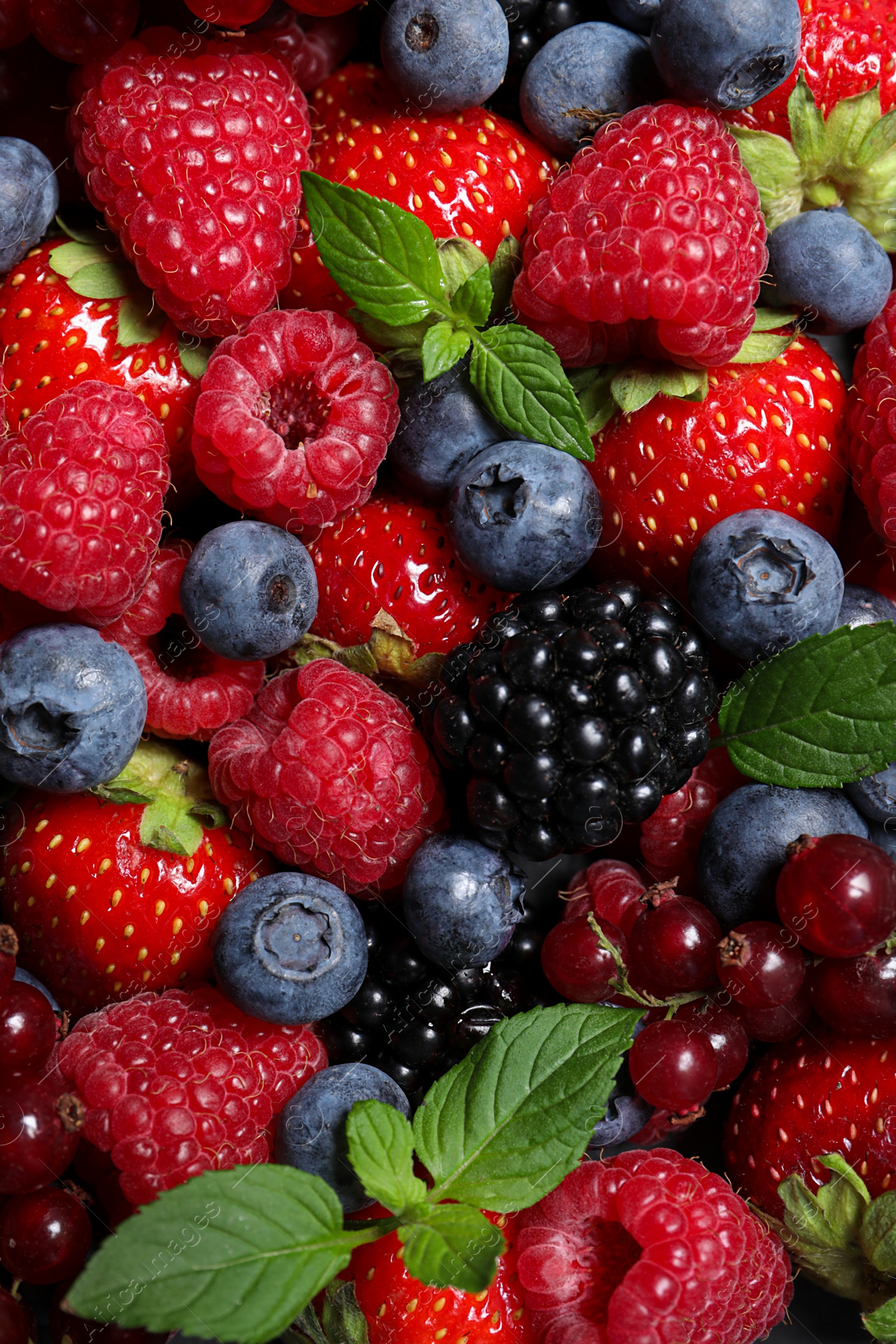 Photo of Assortment of fresh ripe berries with green leaves as background, top view