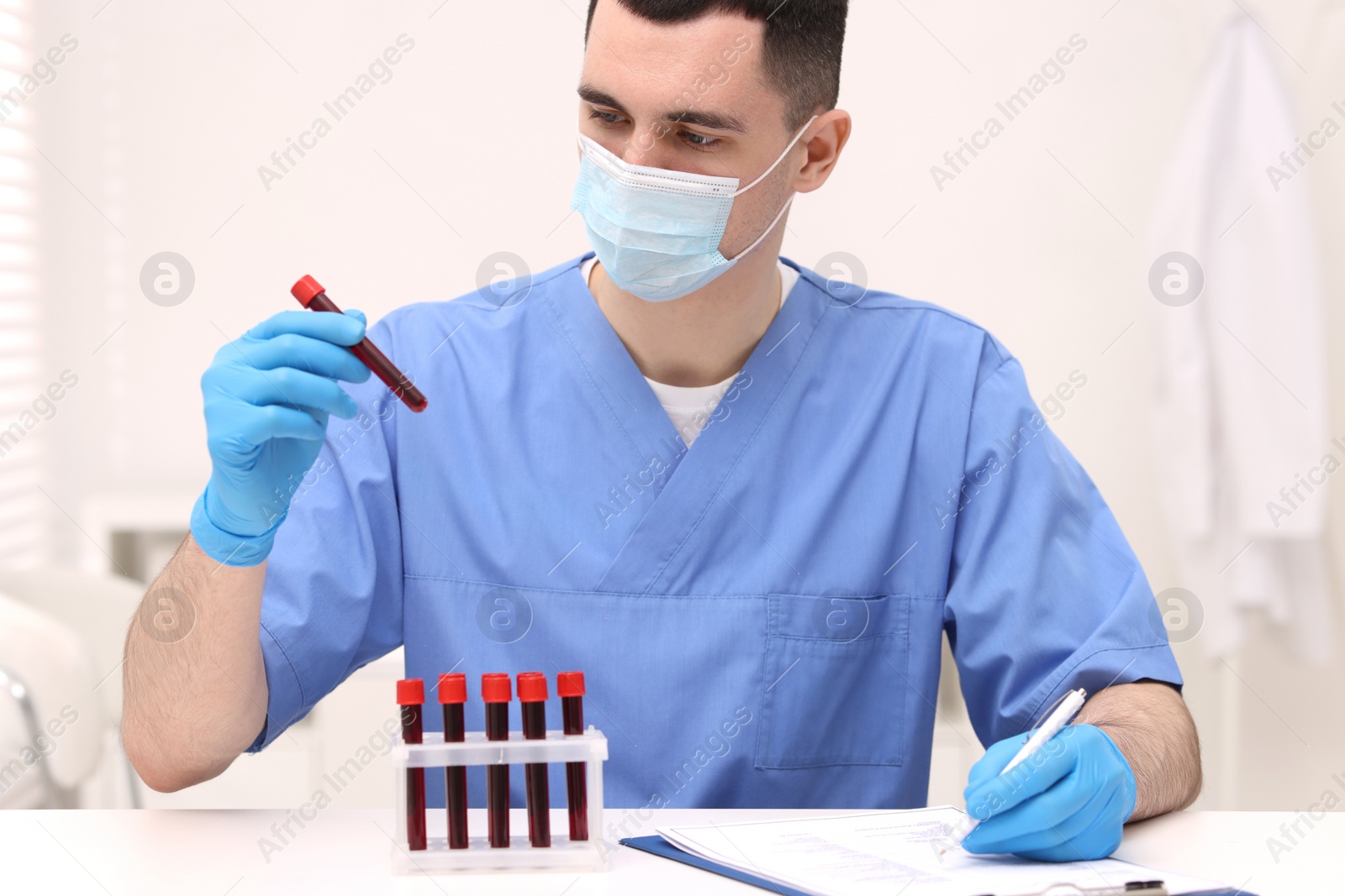 Photo of Doctor with samples of blood in test tubes at white table in hospital