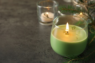 Burning candle with pinecone scent on black table, space for text