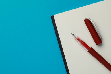 Photo of Notebook and pen on light blue background, top view. Space for text