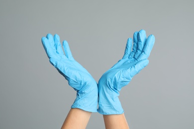 Photo of Doctor wearing medical gloves on grey background, closeup