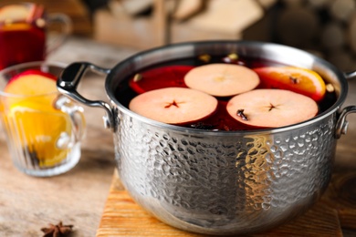 Photo of Delicious mulled wine and ingredients on wooden table, closeup