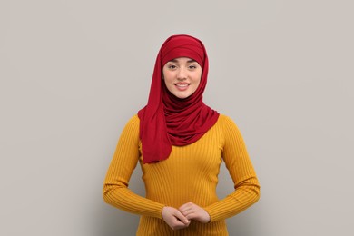 Portrait of Muslim woman in hijab on light gray background