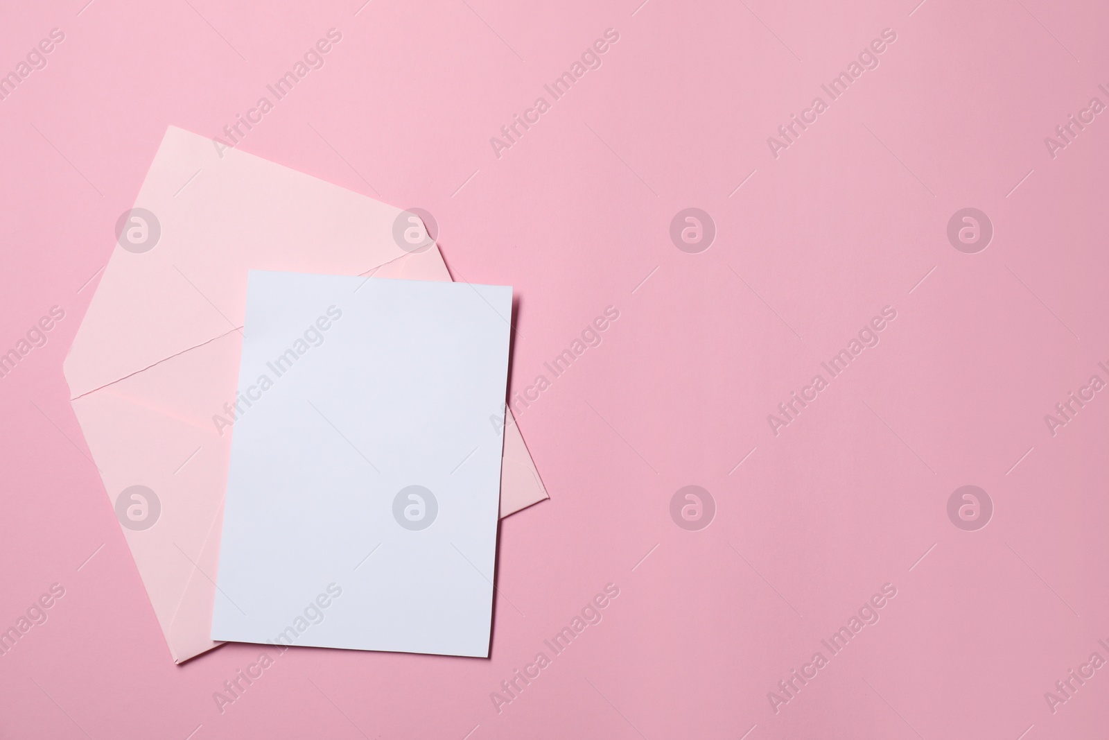Photo of Letter envelope and card on pink background, top view. Space for text