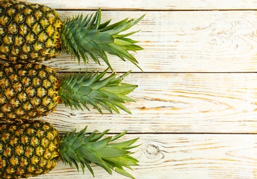 Photo of Fresh pineapples on wooden background, flat lay