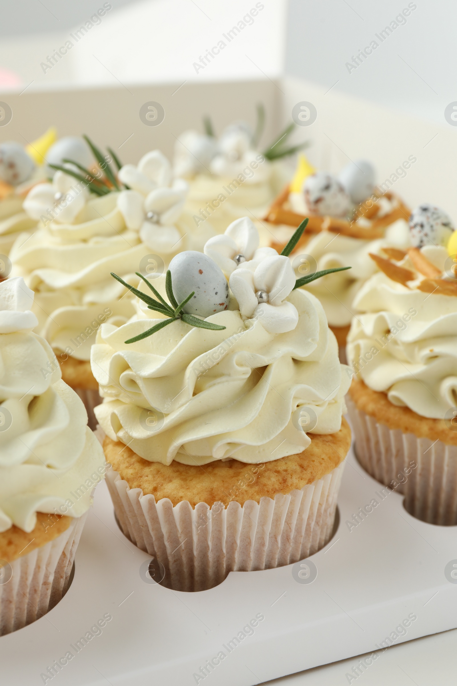 Photo of Tasty Easter cupcakes with vanilla cream in box, closeup