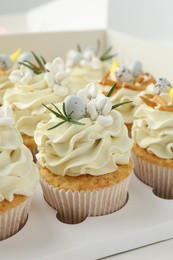 Photo of Tasty Easter cupcakes with vanilla cream in box, closeup