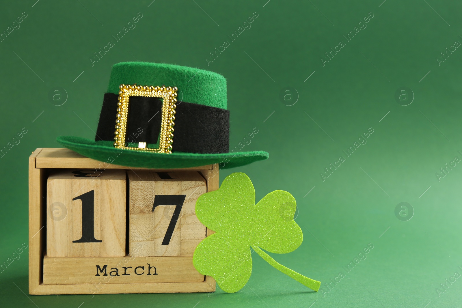 Photo of Leprechaun's hat, block calendar and St. Patrick's day decor on green background. Space for text