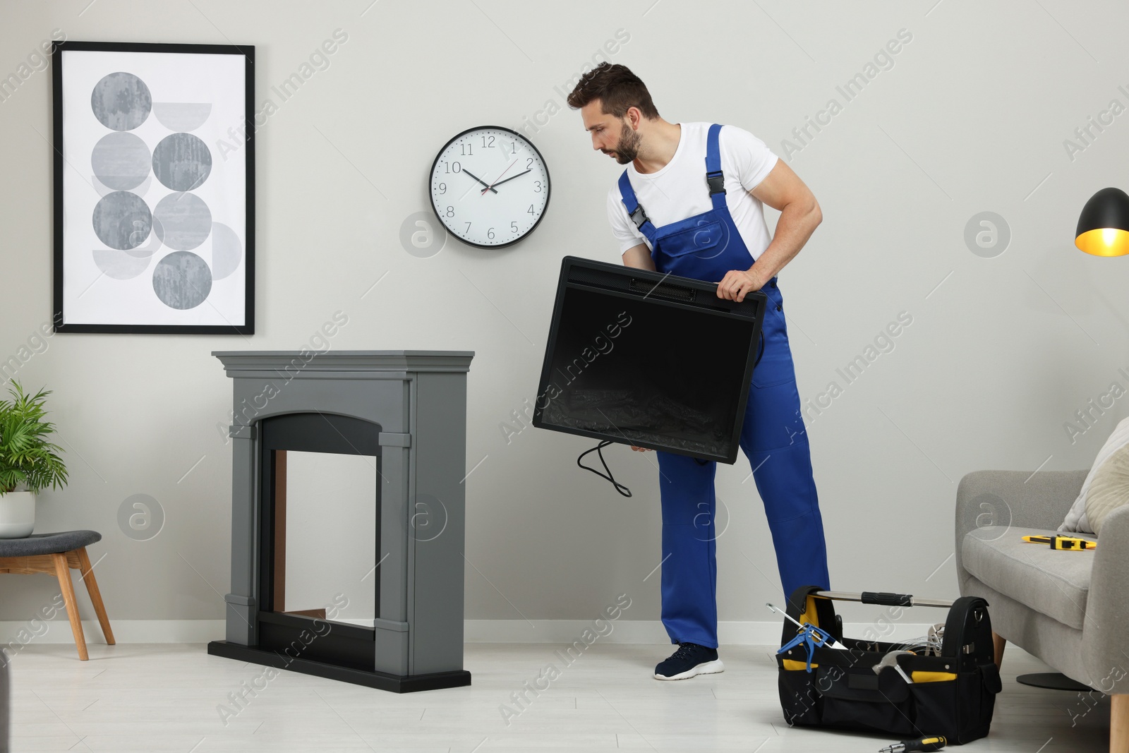 Photo of Professional technician installing electric fireplace in room