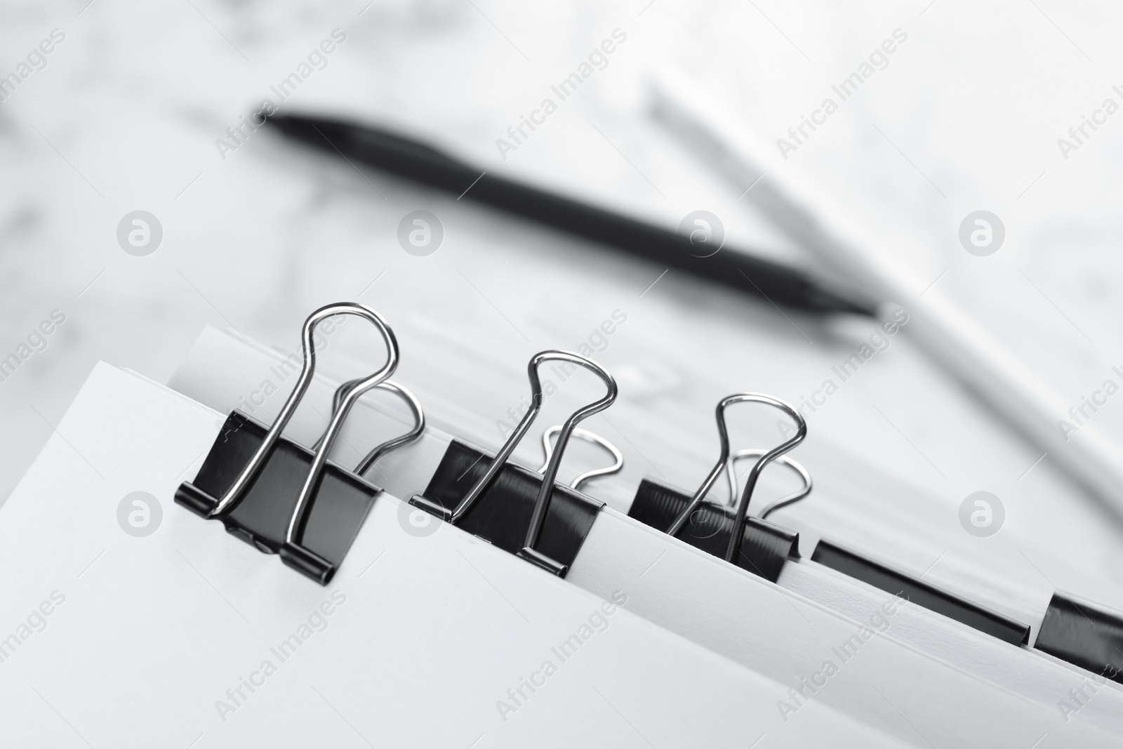 Photo of Pile of documents with binder clips on marble table, closeup