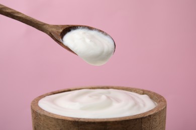 Eating delicious natural yogurt on pink background, closeup