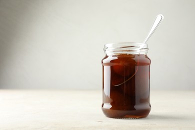 Photo of Jar of tasty sweet fig jam on light table. Space for text
