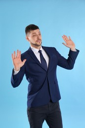 Photo of Man in suit avoiding something on light blue background
