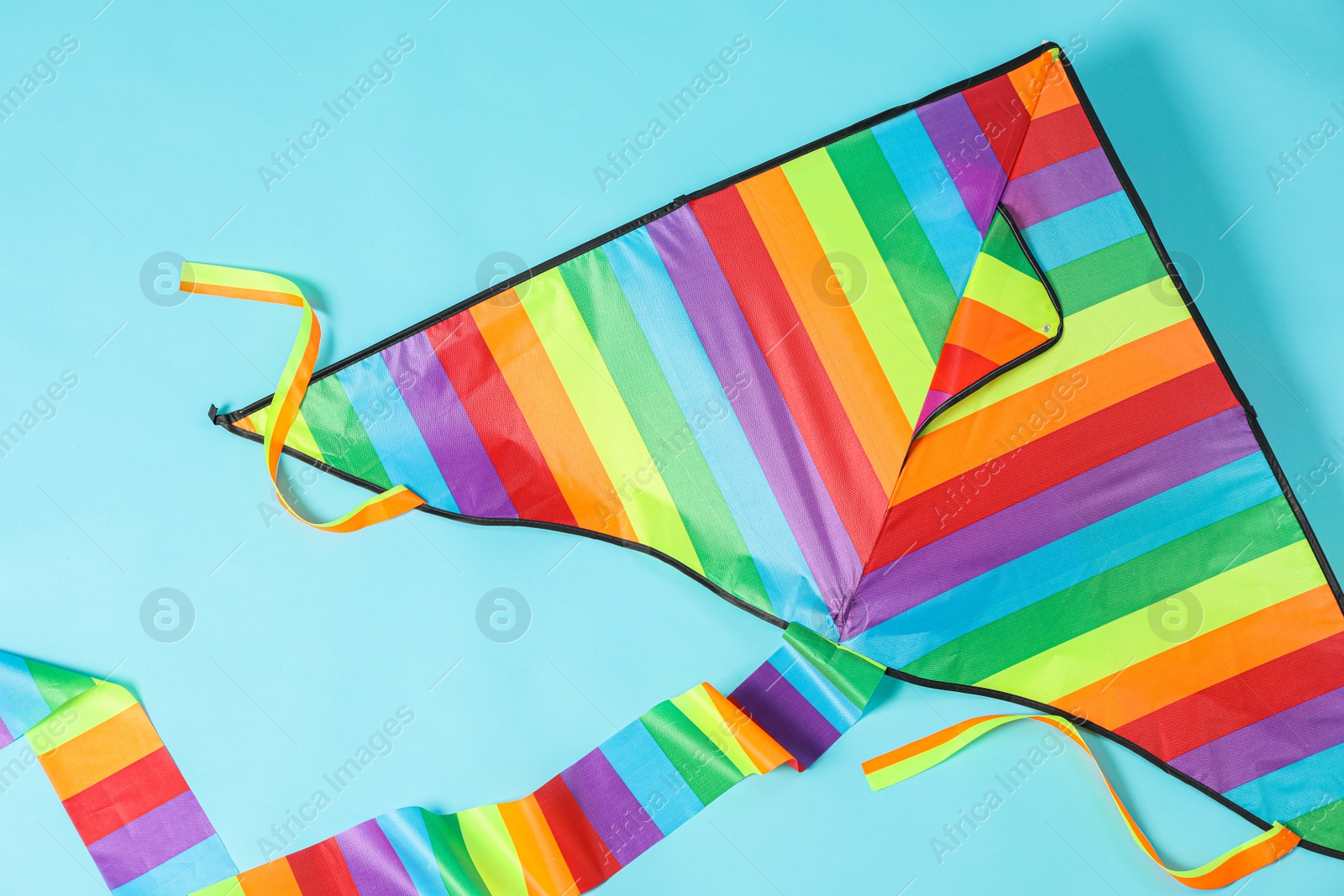 Photo of Bright rainbow kite on light blue background, top view