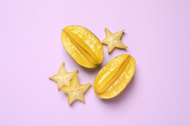 Delicious carambola fruits on violet background, flat lay