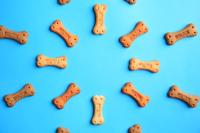Photo of Frame with bone shaped dog cookies on light blue background, flat lay. Space for text
