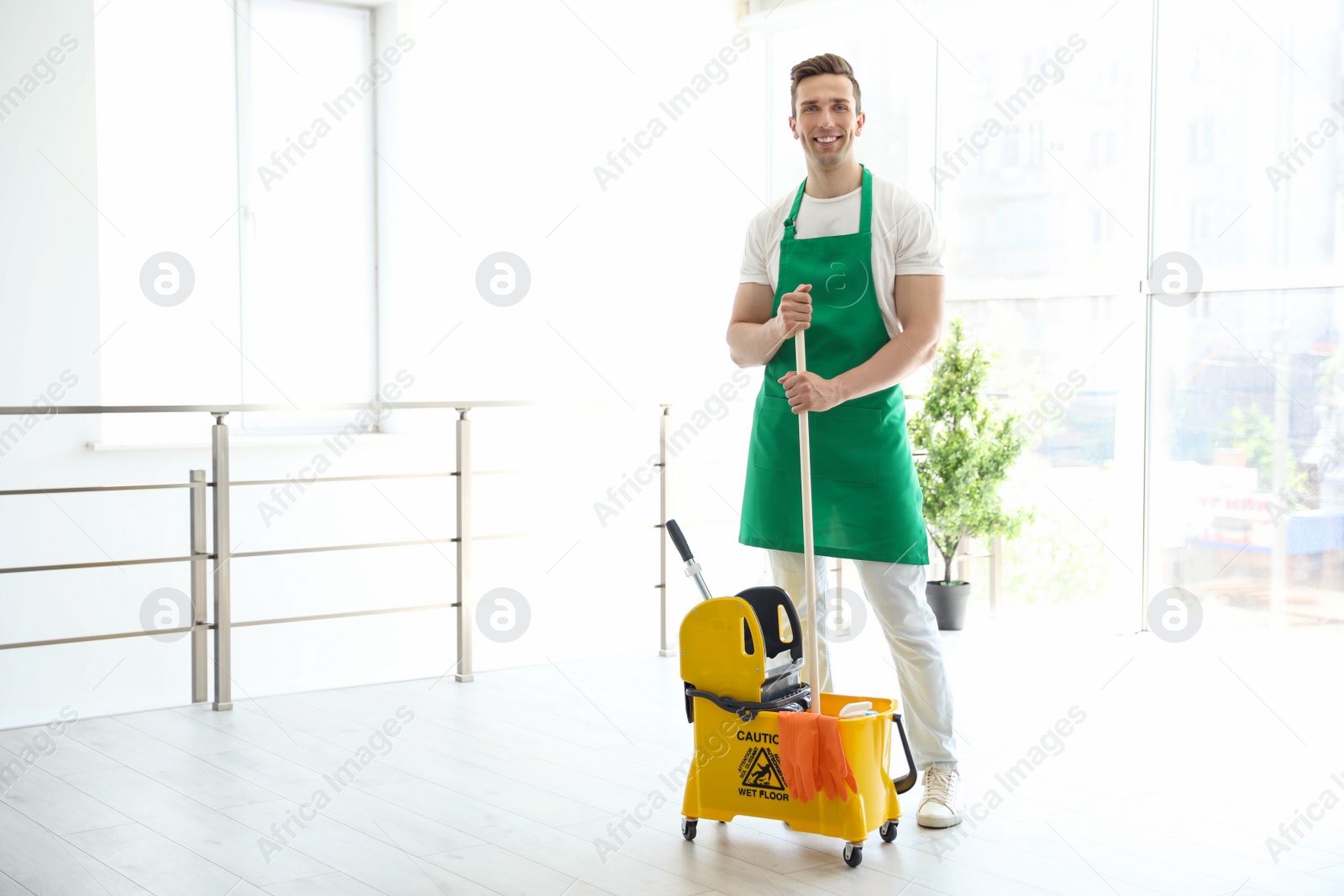 Photo of Young man with mop and bucket cleaning, indoors