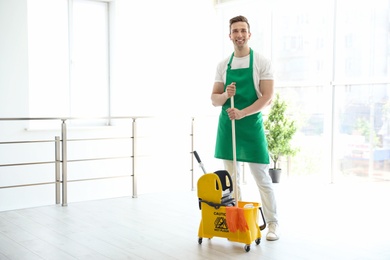 Young man with mop and bucket cleaning, indoors