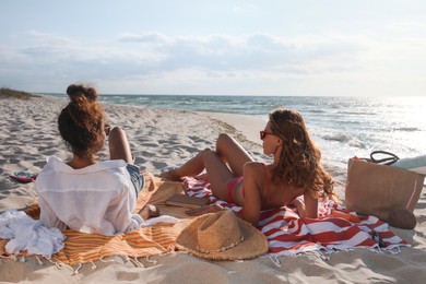 Friends lying on beach towels near sea