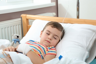 Little child with intravenous drip sleeping in hospital bed