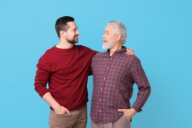 Photo of Happy son and his dad on light blue background