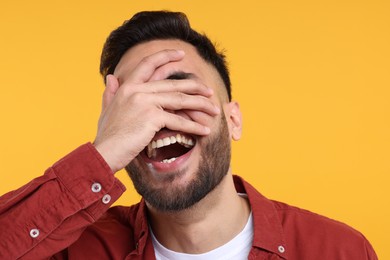 Young man laughing on yellow background, closeup