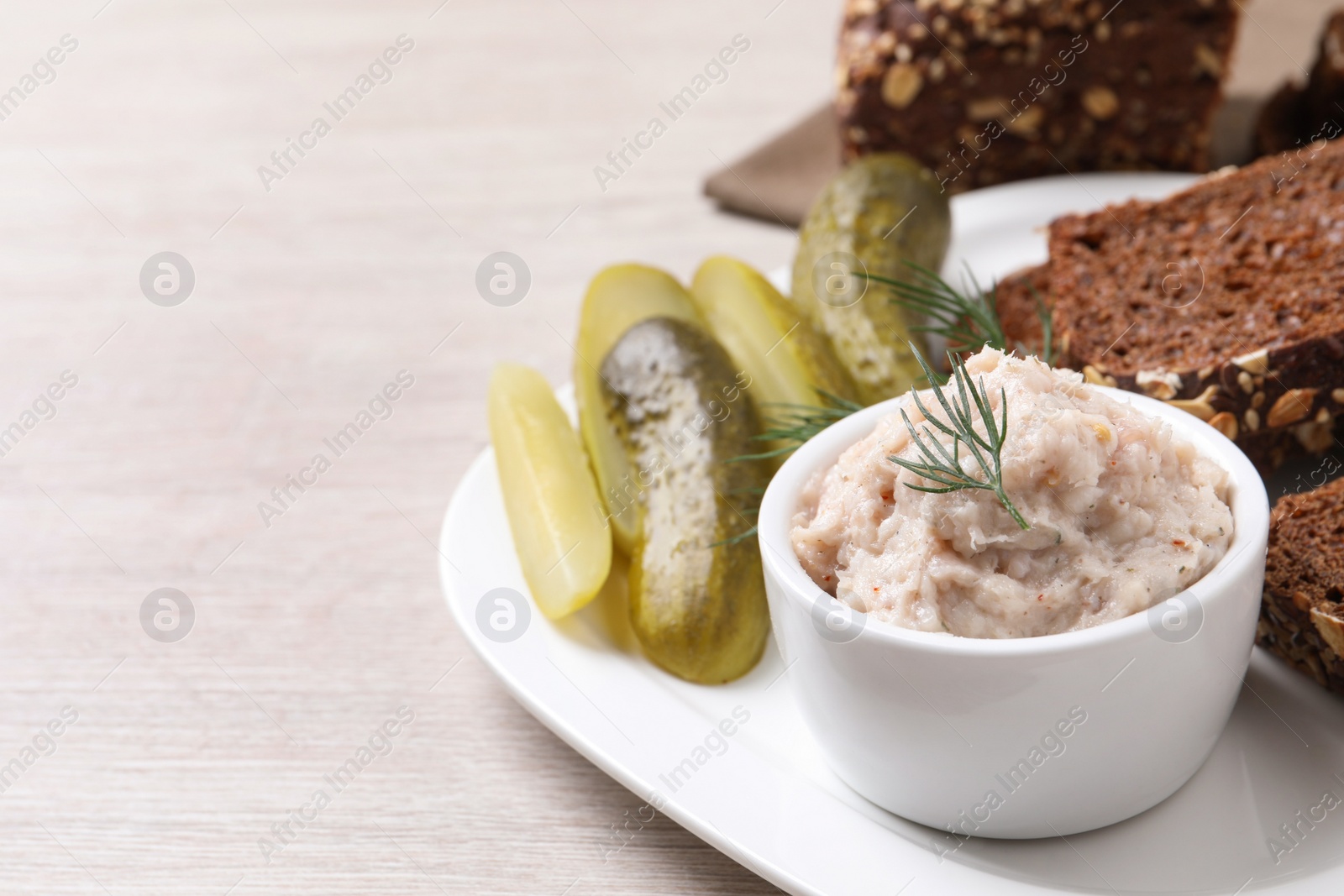 Photo of Delicious lard spread, bread and pickles on wooden table. Space for text