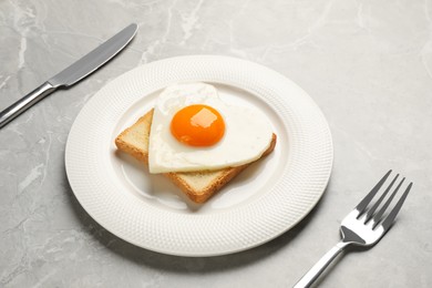 Photo of Tasty fried egg in shape of heart with toast served on marble table