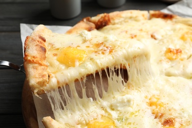 Taking slice of hot cheese pizza Margherita on table, closeup