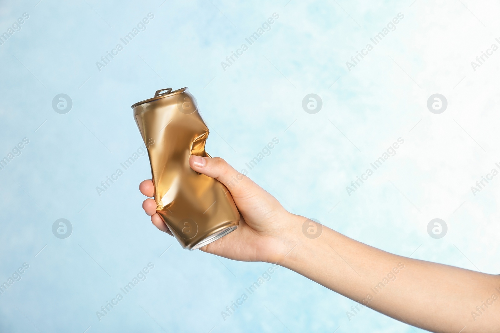 Photo of Woman holding crumpled aluminum can on color background. Metal waste recycling