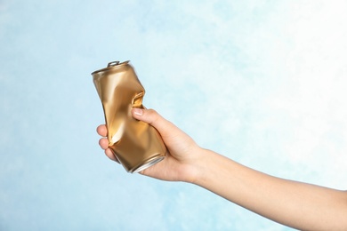 Photo of Woman holding crumpled aluminum can on color background. Metal waste recycling