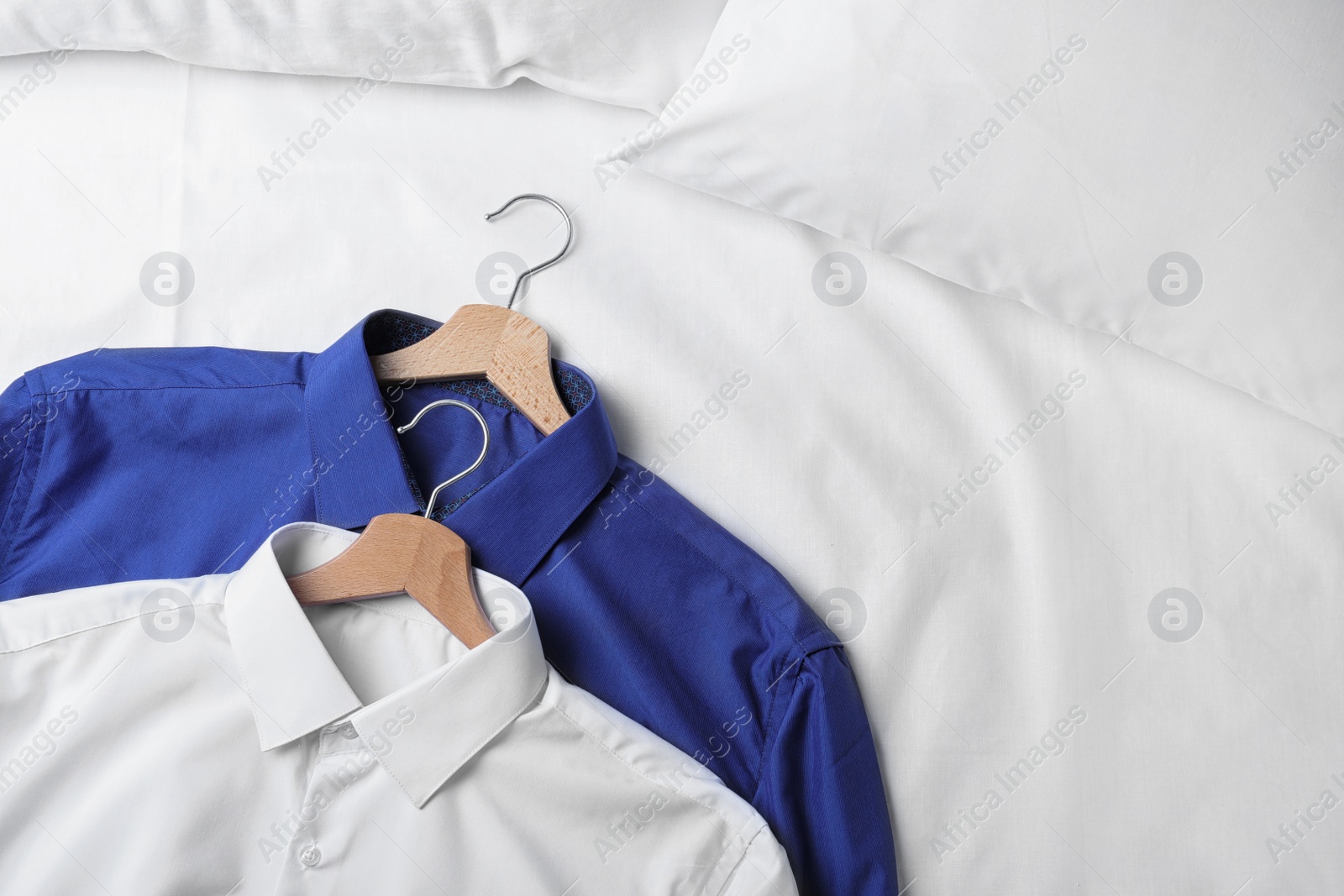 Photo of Stylish shirts on white fabric, closeup. Dry-cleaning service