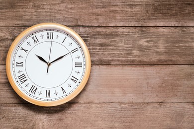 Photo of Stylish round clock on wooden table, top view with space for text. Interior element