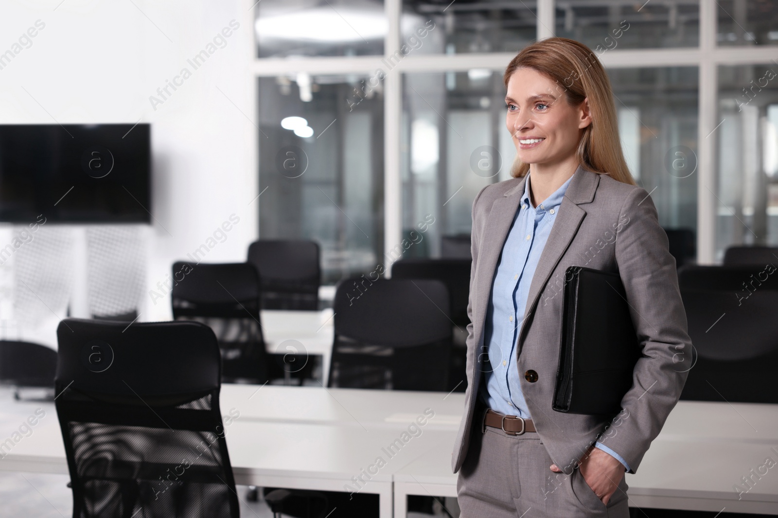 Photo of Happy real estate agent with leather portfolio indoors. Space for text