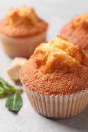 Photo of Delicious sweet muffins on light grey textured table, closeup