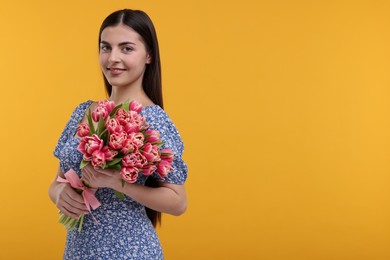 Photo of Happy young woman with beautiful bouquet on orange background. Space for text