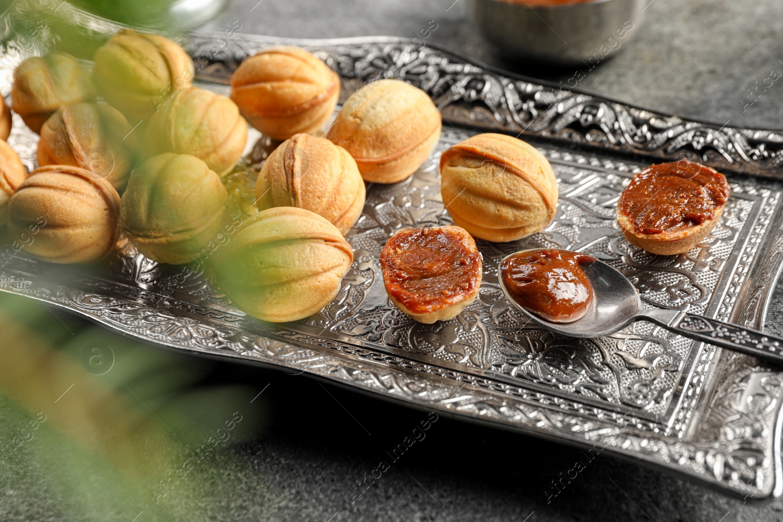 Photo of Homemade walnut shaped cookies with boiled condensed milk on grey table, closeup