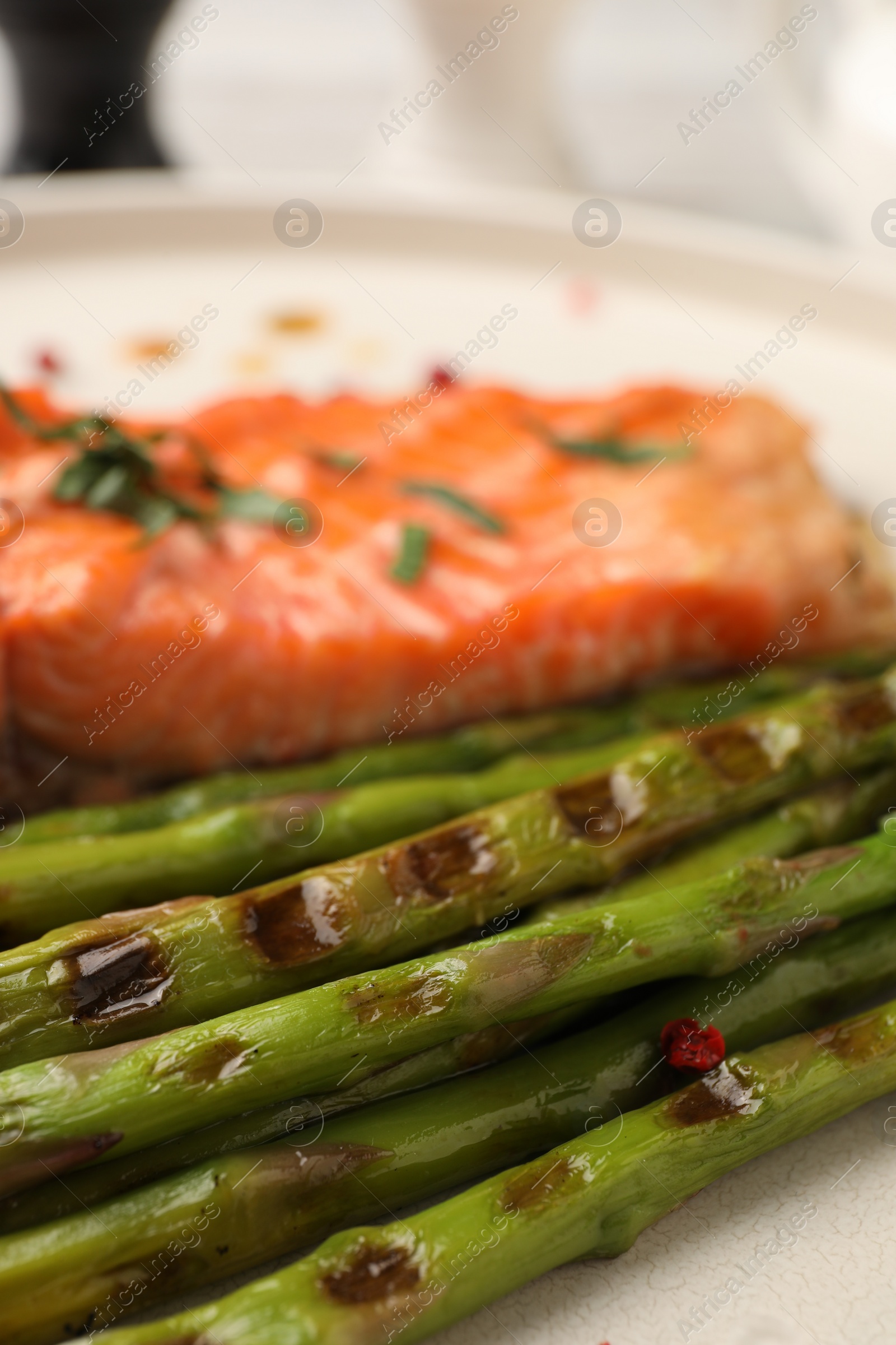 Photo of Tasty asparagus and salmon with spices on plate, closeup