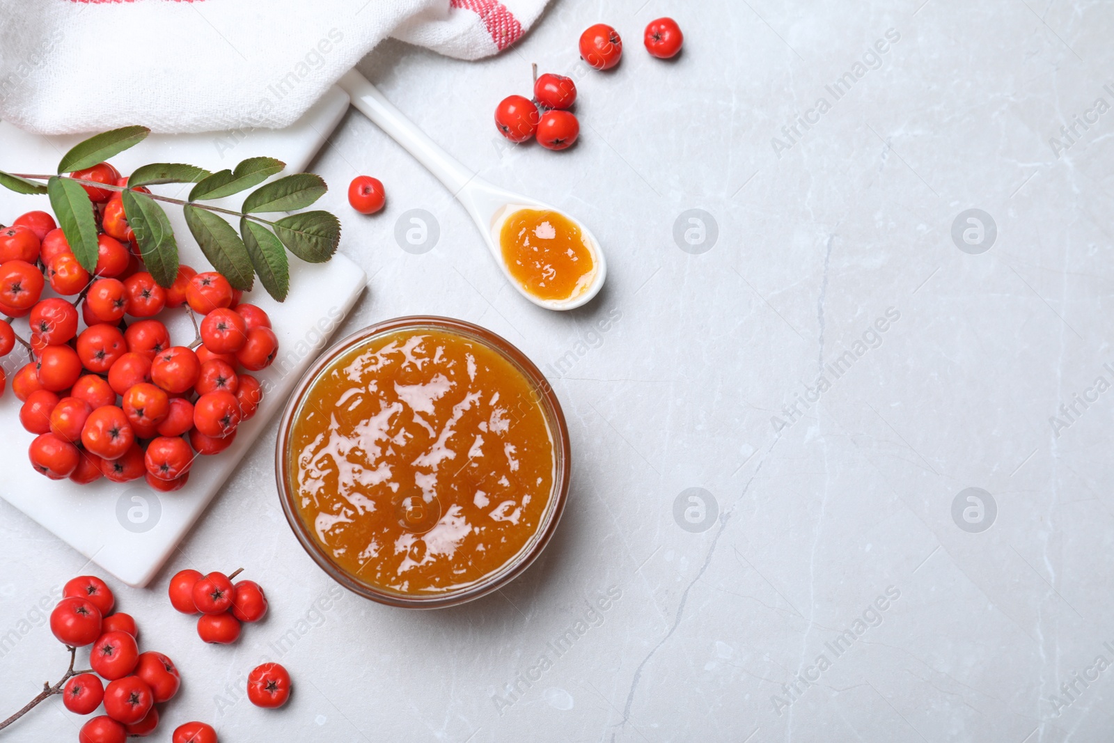 Photo of Delicious rowan jam and berries on light table. Space for text