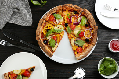 Flat lay composition with vegetable pizza on black wooden table