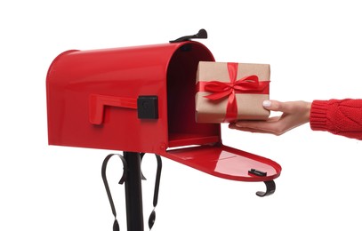 Photo of Woman putting Christmas gift into mailbox on white background, closeup. Sending present by mail